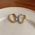 Dettaglio di orecchini a cerchio ovali bicolore oro e argento su un piatto in ceramica - Oro-Argento
