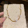 Close-up of 18k gold plated beaded necklace with baroque pearls on textured card - Beaded Pearl Necklace / Gold, White
