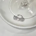 Macro view of a silver bow ear cuff featuring sparkling zircons and a white pearl - Pearl Bowknot Style (HE33345) / Single Piece / Silver