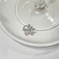 Close-up detail of a silver zircon flower ear cuff on a white ceramic plate background - Flower Style (HE33345) / Single Piece / Silver