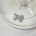 Detailed view of a sparkling silver zircon-studded bow ear cuff on a white ceramic base. - Zirconia Bowknot Style (HE33345) / Single Piece / Silver