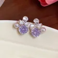 Detailed macro view of elegant purple zircon and pearl flower stud earrings on ceramic dish - Silver-Purple