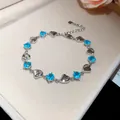 Detailed macro view of heart-shaped silver bracelet featuring sparkling blue gemstones - Bracelet-Blue