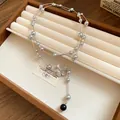 Close-up view of a luxury rhinestone pearl flower pendant necklace on a brown tray - Silver-Grey
