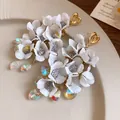 Close-up of elegant white fabric flower earrings with sparkling heart crystals - White