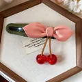 Detail view of pink bow hair clip with red resin cherries and green fabric base. - Single Piece / Pink