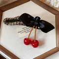 Close-up of fabric bow hair clip with resin cherry charms on a white wooden display. - Single Piece / Black