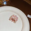 Primo piano di un anello di perline bianche e oro rosa fatto a mano su un piatto - Anello / Oro-Bianco