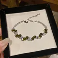 Detailed close-up of a vintage style bracelet with dark green and clear stones in silver - Green