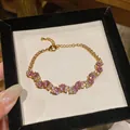 Close-up of a vintage gold bracelet with pink zircons and sparkling gems detail. - Pink