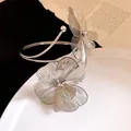 Détail d'un bracelet de bras en métal argenté avec fleurs sur une assiette blanche chic. - Bracelet--Argent