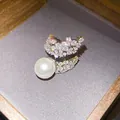 Detailed macro view of an elegant zircon wing open ring with a large lustrous white pearl - Star Wing Style (HR3398)