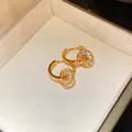Detailed close-up shot of elegant gold pavé double hoop earrings in a jewelry box. - Ear Buckle / Gold