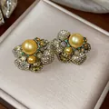 Close-up of vintage-style gold pearl earrings with crystal pavé floral design. - Gold