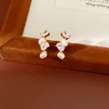 Primo piano di eleganti orecchini di perla ovale con dettagli in zircone lucido - Oro Beige