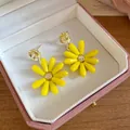 Close-up detail of yellow glass flower drop earrings presented in a pink jewelry box - Yellow