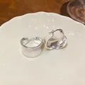 Primo piano di orecchini a cerchio in smalto crema placcati oro 18 carati su piatto - Cerchio Rotondo / Argento-Bianco