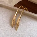 Detailed view of gold curved metal drop earrings on a stone textured tray - 925 Silver Post Style / Gold