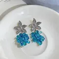 Detalle de pendientes de estrella de mar con colgantes de uvas de cuentas azules en plato - Azul