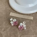 Close-up detail of pink flower earrings featuring zircon stones and small pink pearls - Pink