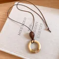 Detailansicht der Ethno-Halskette mit Harzanhänger und Lederkordel auf Kunstbuchhintergrund. - 6# Halskette (ai-Stil 6) / Kaffeebraun