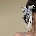 Gros plan d'une pince à cheveux à nœud bleu et blanc avec perles sur cheveux sombres. - Bleu