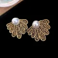 Detailed macro view of vintage gold hollowed leaf stud earrings featuring elegant white pearls - Gold