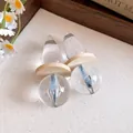Detailed view of clear resin pendant earrings with wooden discs and blue glitter - Silver Earring Post Style / Transparent Coffee