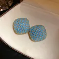 Detailed macro shot of vintage palace style square stud earrings with blue stone inlay design - Gold-Blue