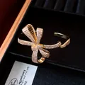 Close-up of elegant 18K gold plated bow cuff bracelet with sparkling zirconia pavé setting - Gold