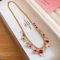 Detail van gouden ketting met kleurrijke harsbloemen in een stijlvol sieradendoosje. - Ketting / Goud-Meerkleurig