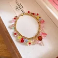 Detail van een kleurrijke harsbloem armband met goudkleurige roestvrijstalen ketting. - Armband / Goud-Meerkleurig