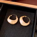 Close-up detail of high-end 18K gold-plated earrings with refined brushed texture. - Gold