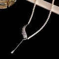 Close-up of elegant pearl necklace featuring a zircon angel wing and waterdrop pendant. - Silver