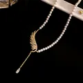 Close-up of elegant pearl necklace with zircon wing and drop pendant detail. - Gold