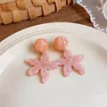 Primo piano di orecchini a forma di stella marina in resina marmorizzata rosa su piatto bianco - Rosa