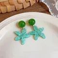 Primo piano di orecchini a stella marina verdi bohémien su un piatto di ceramica - Blu