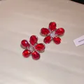 Detailed macro view of elegant red crystal flower stud earrings with high-quality silver needles - Red