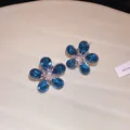 Macro view of blue crystal flower earrings with silver needles and exquisite details - Blue