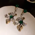 Detailed shot of vintage gold flower earrings with emerald green crystals and sparkling rhinestones - Antique Gold
