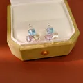Macro detail of geometric square colored glass stud earrings inside a green velvet box - Hoop-Pink-Blue-Green