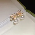Dettaglio ravvicinato di eleganti orecchini a lobo a fiore placcati oro 18k con perle - Fiore Rosa / Oro