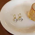 Elegante hartvormige hars oorbellen met zirkonia-rand gepresenteerd op een wit bord - Goud
