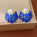 Boucles d'oreilles vintage en or avec pierres bleues et perle sur une boîte à bijoux. - Bleu clair