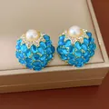 Détail de boucles d'oreilles vintage en or avec perle centrale et pierres bleues - Rose bonbon