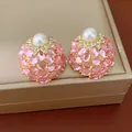 Gros plan de boucles d'oreilles vintage roses avec perles et strass brillants. - Rose