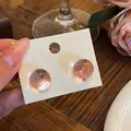 Pink resin sphere stud earrings shown on a white display card in a lifestyle setting - Round Style (HE33609-) / Pink