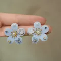 Close-up of light blue flocked flower earrings with pearls and butterfly charms - Style 23 (Silver Pin-Gold) / Blue