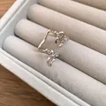 Detailed close-up of a silver bow double-layer ear cuff resting in a grey velvet jewelry tray. - Clip-On Earrings / Silver