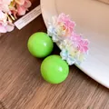 Close-up detail of sweet resin flower earrings with light green spherical studs - Floral Round Bead Shape / Green